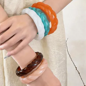 Eleganti bracciali rigidi intrecciati in acrilico in vari colori indossati sul polso