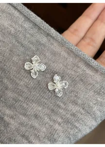 Detailed macro view of clear zircon flower stud earrings on grey knit fabric