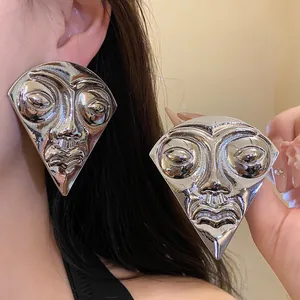 Detailed view of oversized vintage silver fan-shaped earrings with a unique human face relief