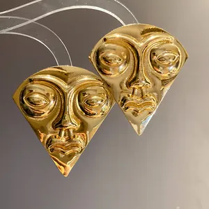 Close-up of vintage gold fan-shaped stud earrings with abstract face portrait design