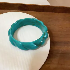Vista macro dettagliata di un bracciale rigido retrò in acrilico verde acqua intrecciato