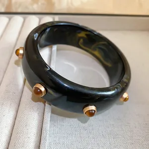 Gros plan d'un bracelet jonc rétro en résine avec clous ambrés sur plateau à bijoux