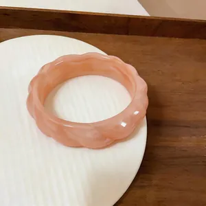 Dettaglio del bracciale in acrilico pesca con trama marmorea su un piatto