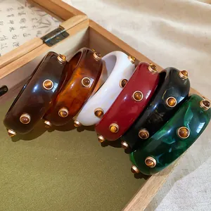 Détail montrant un groupe de joncs rétro en résine avec rivets métalliques colorés
