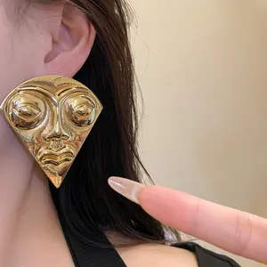 Close-up detail of large vintage fan-shaped golden portrait earrings worn by a female model