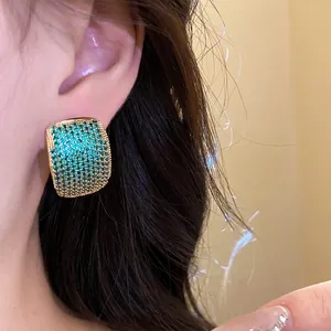 Elegant vintage C-shaped stud earrings with green zircon stones shown on Asian model