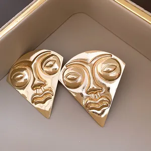 Detailed view of retro gold fan-shaped stud earrings with artistic abstract face design