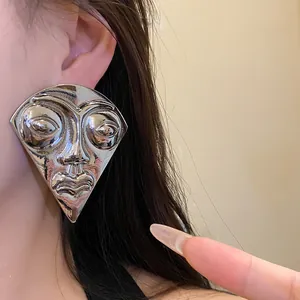 Detail view of a vintage oversized silver abstract face mask stud earring for women.