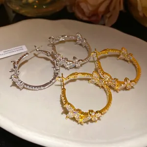 Elegant 18k gold-plated butterfly hoop earrings with zircon stones on white ceramic plate