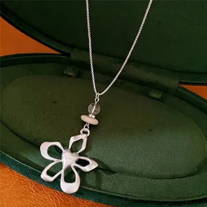 Elegant flower pendant necklace with glass and stone beads displayed in a green gift box.