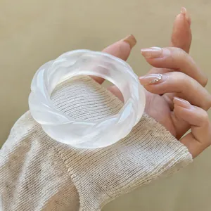 Elegante primo piano di un bracciale rigido in acrilico bianco ritorto indossato al polso
