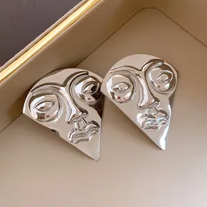 Abstract face design silver stud earrings with high-polish metallic finish details.