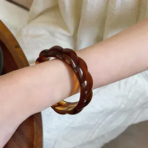 Dettaglio di un bracciale rigido in acrilico marrone retrò attorcigliato