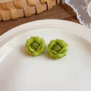 Vista ravvicinata di orecchini a forma di fiore verde su un piatto di ceramica.