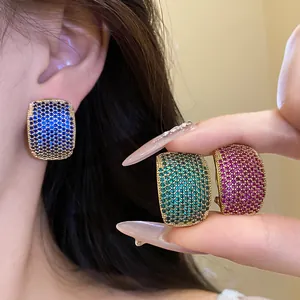 Close-up of vintage C-shaped earrings with colorful zircon stones in three colors