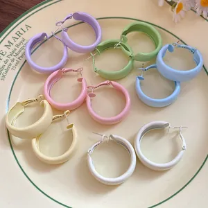 Close-up of colorful pastel enamel hoop earrings on a vintage French style ceramic plate