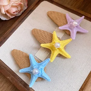 Detailed view of colorful raffia starfish hair clips with faux pearls on linen backdrop