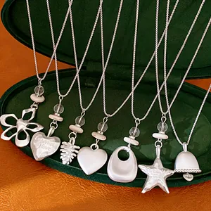 Close-up of silver necklaces with star, heart, and flower pendants inside a jewelry box.