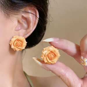 Vista dettagliata di orecchini a rosa arancione con petali finemente rifiniti.