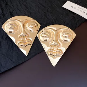 Detailed view of vintage gold-toned fan-shaped earrings featuring an artistic portrait relief