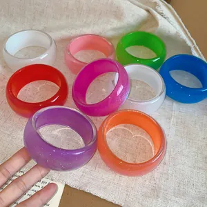Close-up of colorful chunky resin bracelets with iridescent glitter finish and geometric design