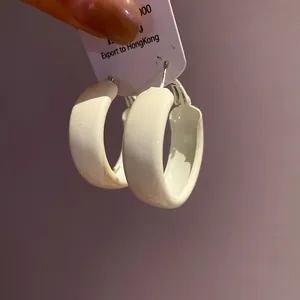 Detailed macro view of minimalist white painted thick C-shape hoop earrings for women