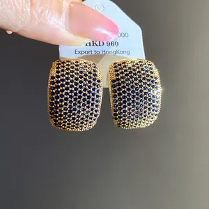 Macro detail of vintage gold-plated C-shaped stud earrings encrusted with dark blue zircons