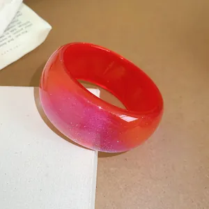 Detailed macro view of a red and pink gradient resin bangle with subtle glitter shimmer