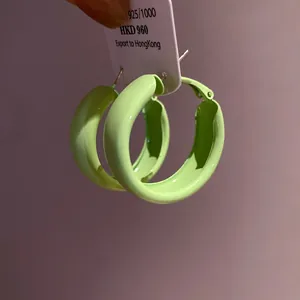 Close-up macro detail of light green spray-painted hoop earrings featuring silver needles