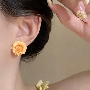 Dettaglio ravvicinato di un orecchino a rosa gialla placcato oro 18K su una modella