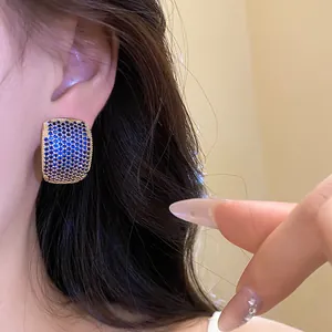 Detailed macro view of vintage luxury blue zirconia C-shape stud earring worn on model ear