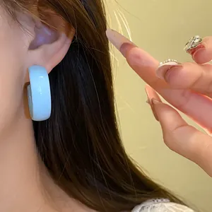 Close-up detail of light blue spray-painted round hoop earring worn on a model's ear