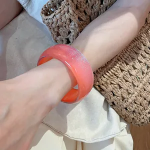 Close-up of a coral resin geometric bangle bracelet with sparkling silver glitter finish
