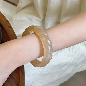 Primo piano dettagliato di un bracciale rigido vintage in acrilico color crema al polso