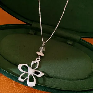 Detailed view of elegant silver flower pendant necklace with beads in a green velvet box