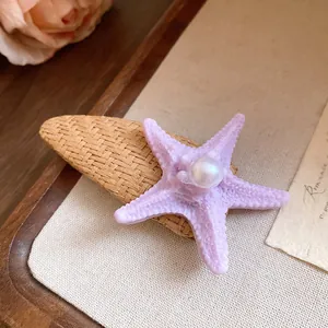 Close-up detail of a purple starfish hair clip featuring a white pearl and raffia weave