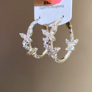 Close-up detail of silver-toned zircon butterfly hoop earrings with sparkling stones