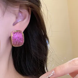 Close-up of vintage-style C-shaped earring with magenta pavé-set stones on a model's ear