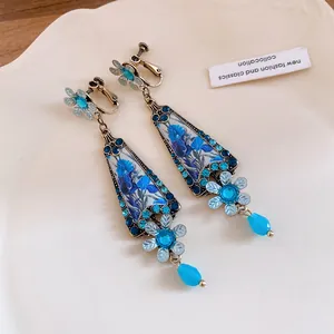 Close-up of vintage resin flower earrings with blue rhinestones and gold-tone finish