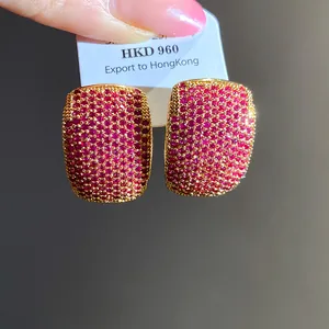Close-up of vintage C-shape gold stud earrings with dense red zircon pavé setting