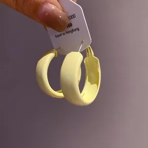 Detail showing minimalist pale yellow spray-painted hoop earrings with silver needles