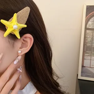 Detail showing a yellow raffia starfish hair clip with a pearl on a person's hair