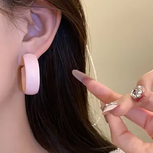 Macro detail shot of a sweet pink painted C-shaped hoop earring elegantly worn on ear