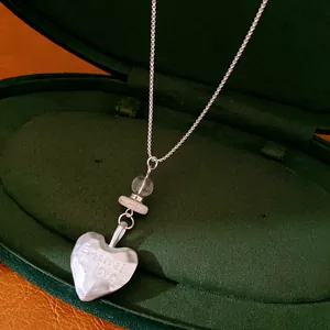 Close-up of a heart pendant necklace with 'Eternal my love' engraving in a box