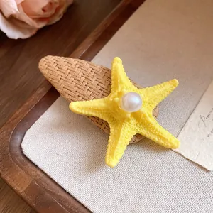 Macro view of yellow starfish hair clip with pearl detail on raffia base