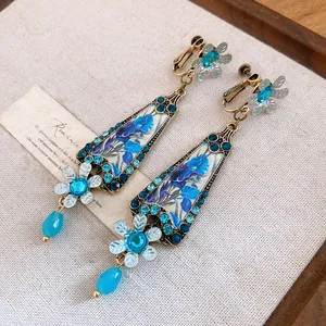 Detailed view of vintage resin flower earrings with blue rhinestones