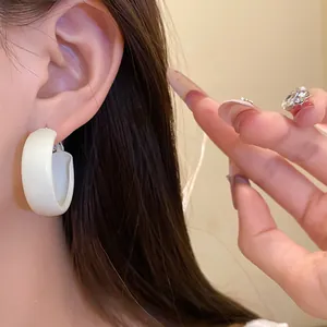 Close-up detail of a minimalist cream spray-painted thick hoop earring on an Asian model