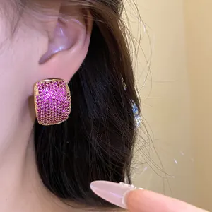 Detailed close-up of vintage gold-plated C-shaped earrings with pink pavé zircons