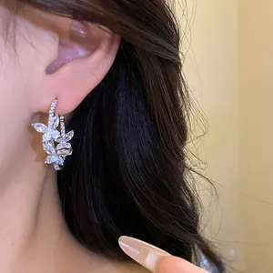 Close-up detail of silver butterfly hoop earrings with sparkling zircon stones on ear.