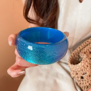 Detailed close-up of a blue resin geometric bangle with sparkling glitter finish.